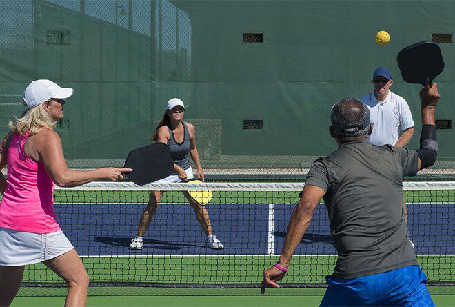 Elderly group playing doubles pickleball