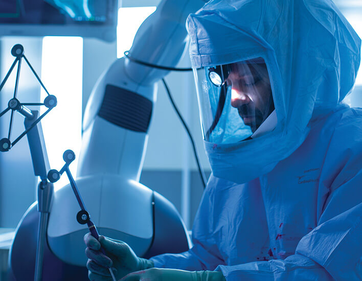 doctor in protective gear using surgical equipment