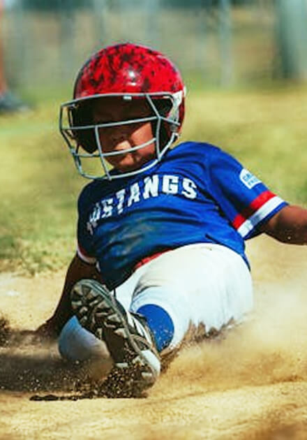 boy in baseball uniform sliding into base