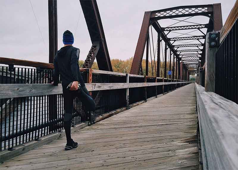 runner stretching on bridge