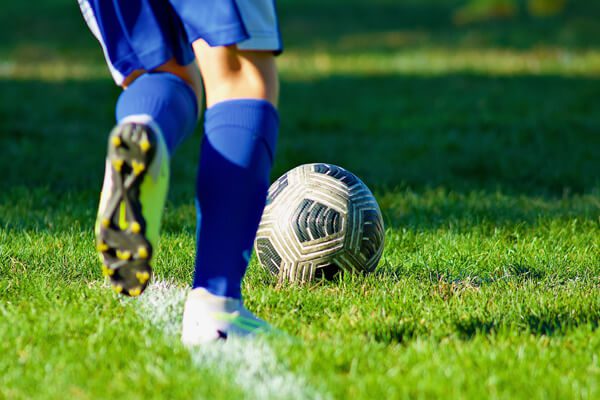 boy kicking soccer ball down field