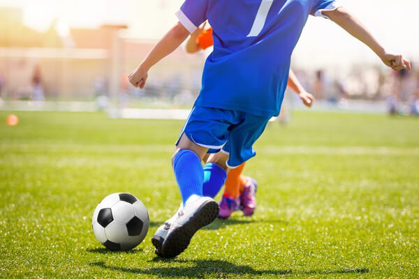 boy kicking soccer ball past opponent