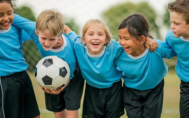 children playing soccer and huddling wearing blue jerseys