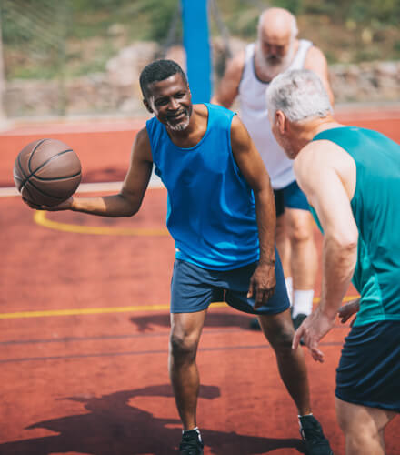 senior men playing basketball outdoors