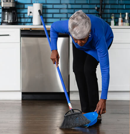 woman sweeping floor with broom and dust pan