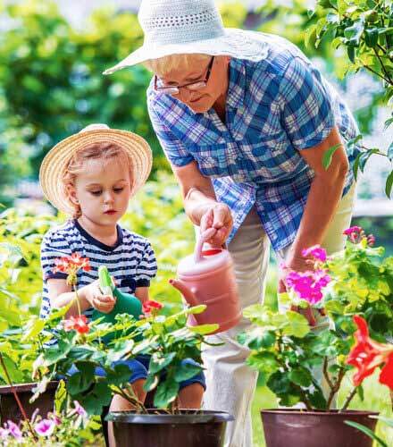 grandmother watering flowers with granddaughter