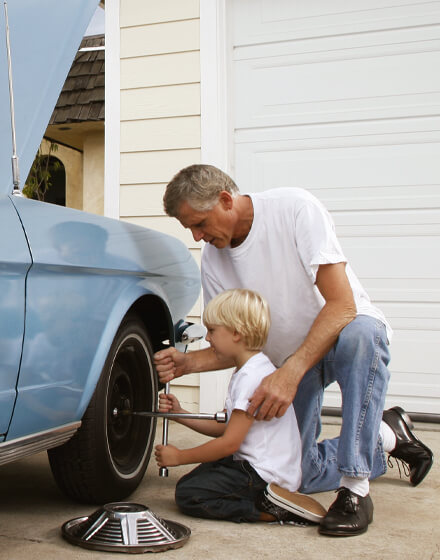 man working on an automobile tire with boy