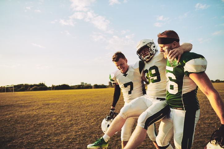 football players carrying injured teammate