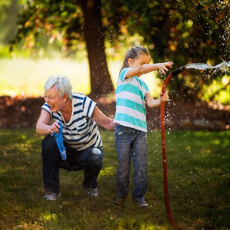 grnadmother and granddaughter playing outside with the hose