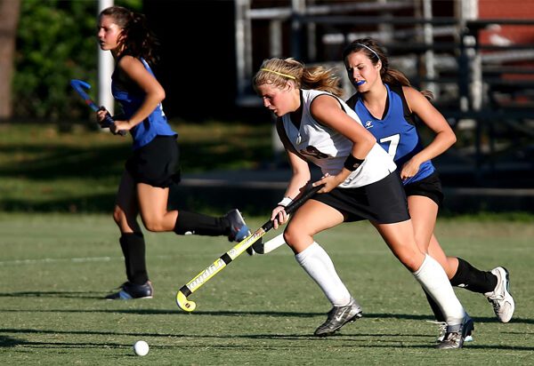 Lacrosse players running on the field