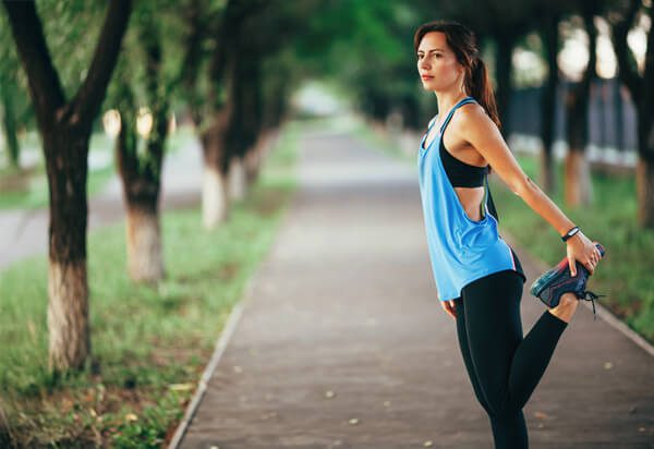 female runner stretching knee and acl