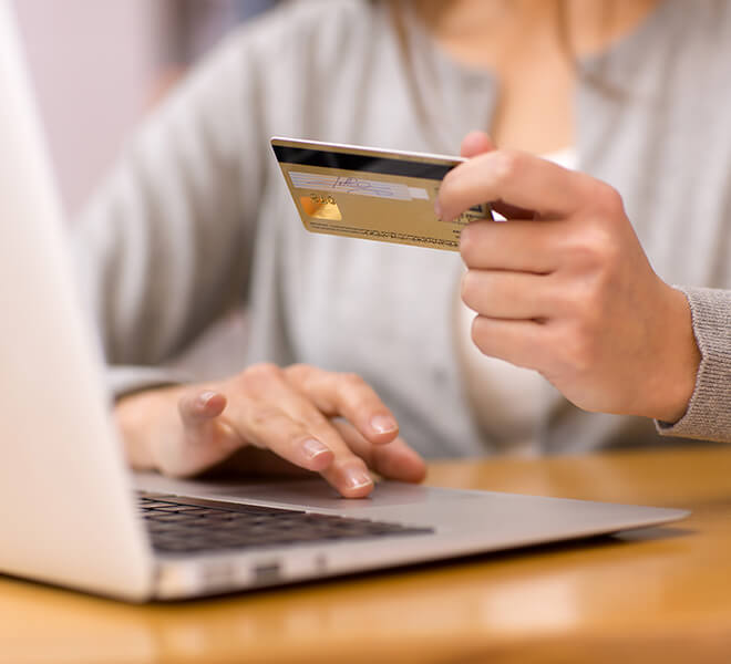 Close up of woman using credit card at laptop