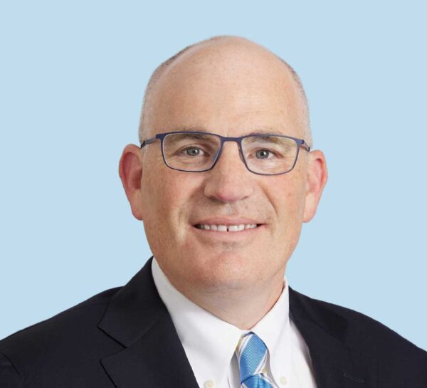 Andrew J. Cooper professional headshot wearing black suit with striped tie