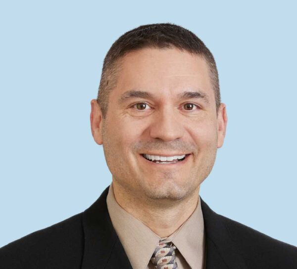 Anthony Marcotte professional headshot wearing black suit with brown patterned tie