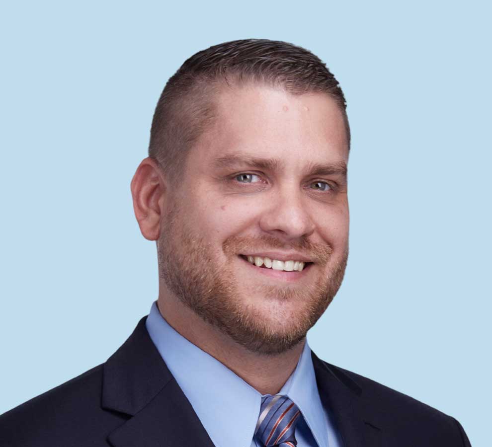 Benjamin J. Maxson, DO professional headshot wearing black suit and striped tie