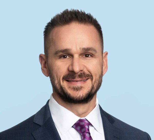 Christopher E. Baker, MD professional headshot wearing navy textured suit with purple tie