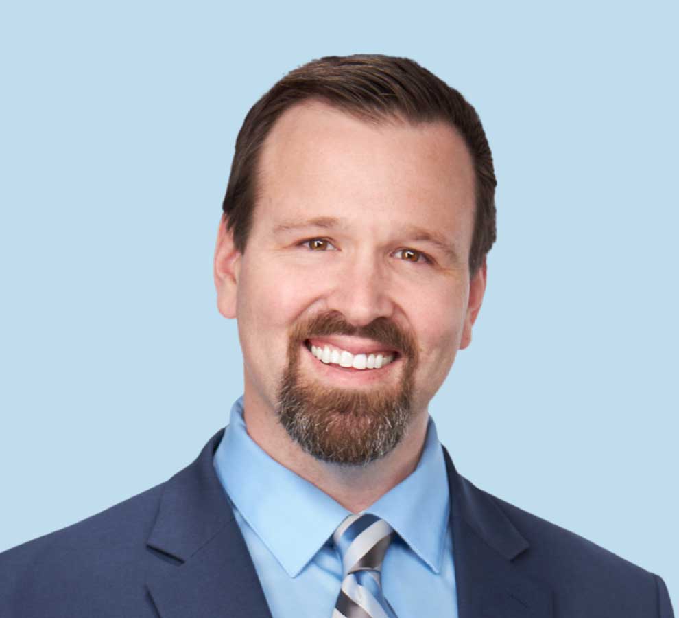 Devin W. Collins, DO professional headshot wearing navy blue suit with striped tie