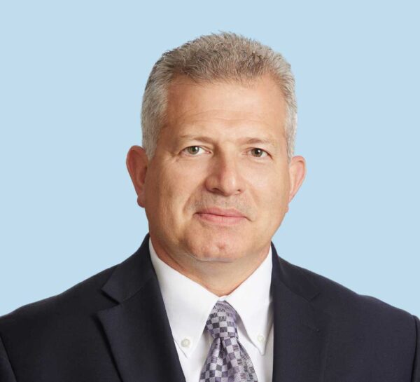 George Canizares, MD professional headshot wearing black suit with gray checkered tie