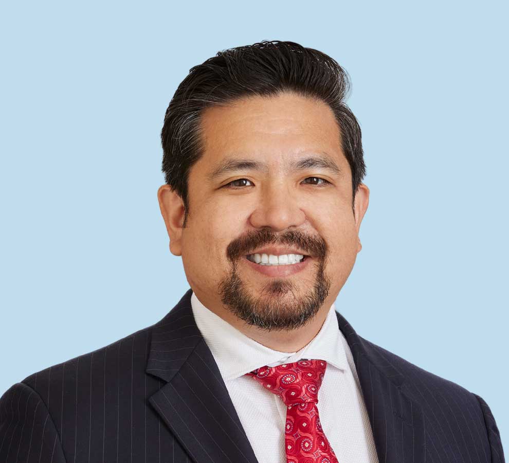 George Feliciano, MD professional headshot wearing black suit with red patterned tie