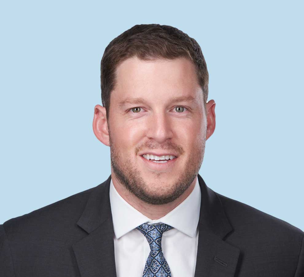 Gregory I. Mines, MD professional headshot wearing black suit with blue pattered tie