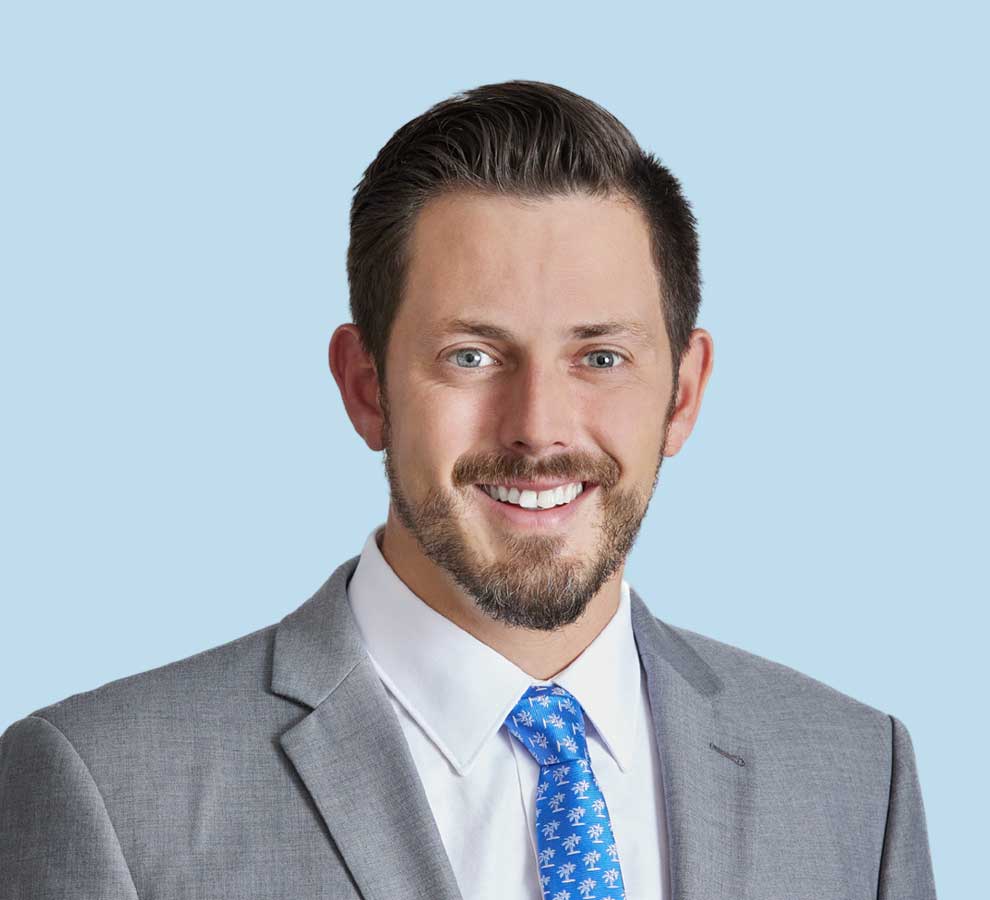 Holden Heitner, MD professional headshot wearing gray suit with blue palm tree tie