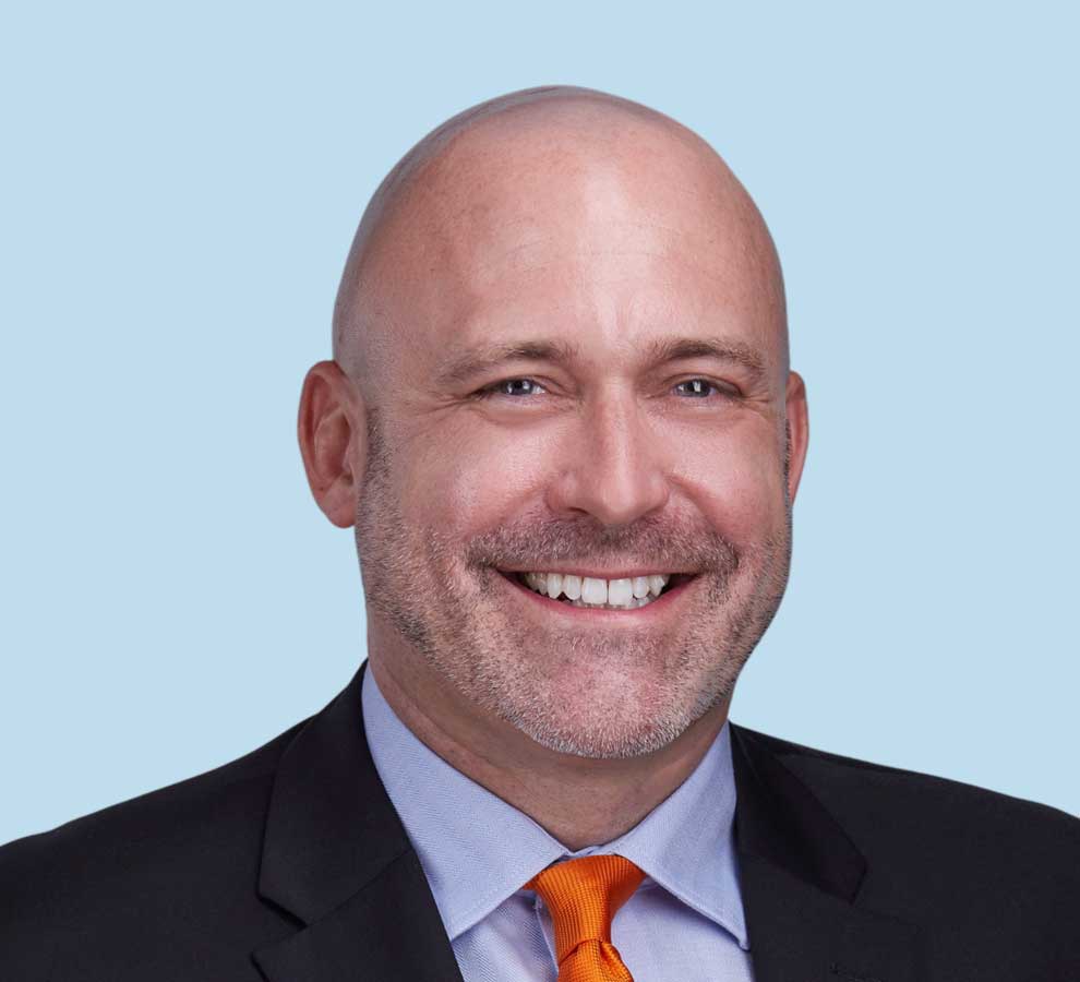 Jeff E. Sellman, MD professional headshot wearing black suit and orange tie