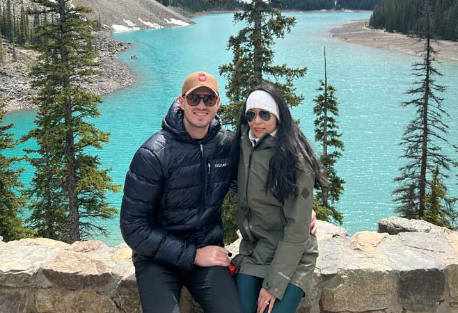 Jeffrey Kannen with wife in front of a scenic lake view with pine trees