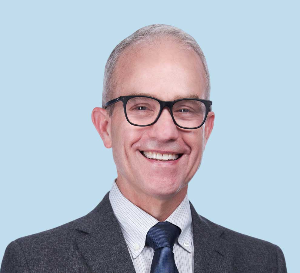 John M. Small, MD professional headshot wearing gray textured suit with navy tie