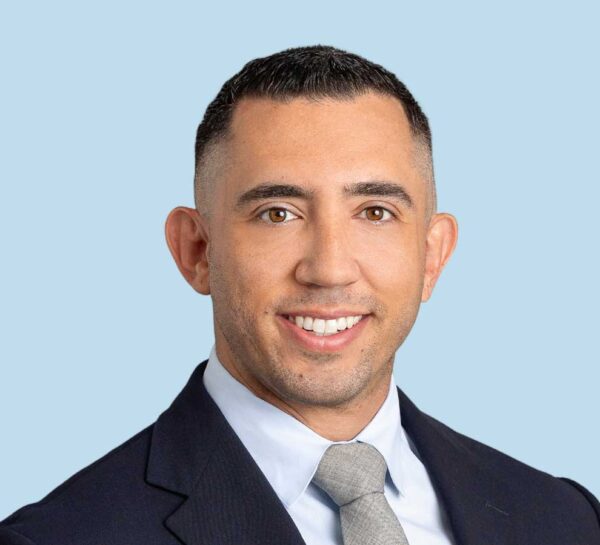 Joseph D'Alonzo, DC professional headshot wearing black suit with gray tie