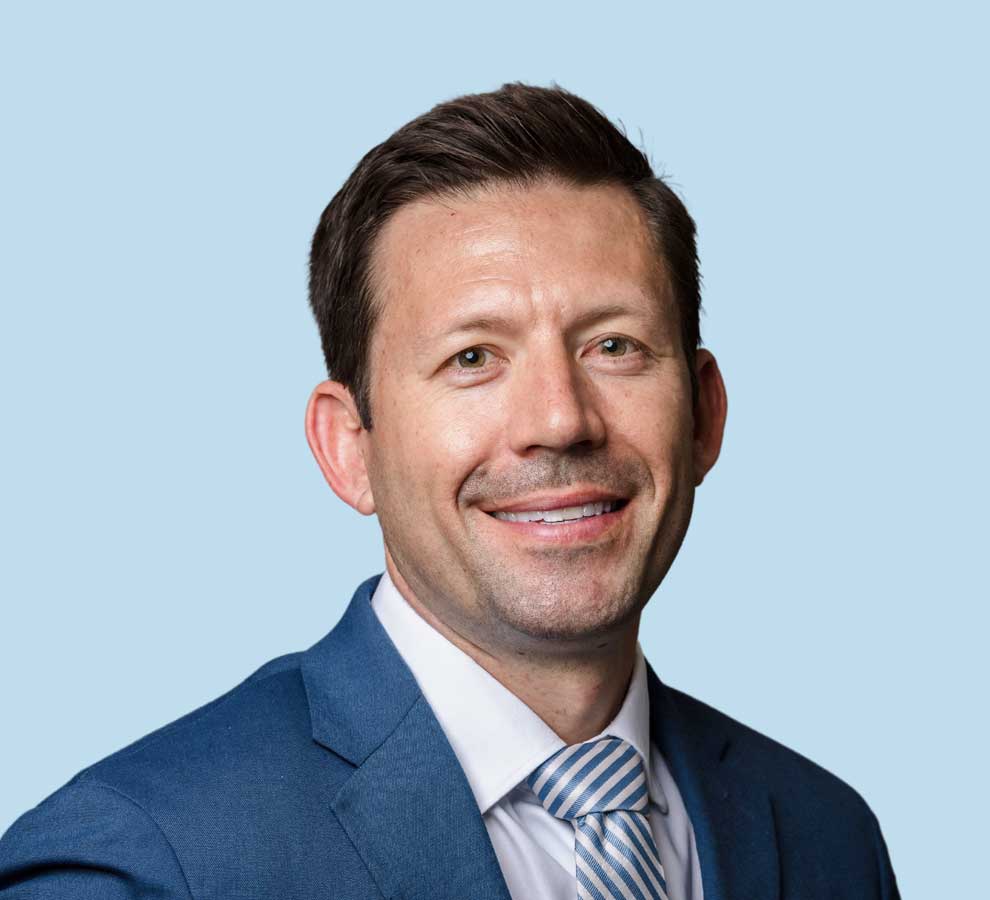 Justin Deen, MD professional headshot wearing blue suit with blue and white striped tie