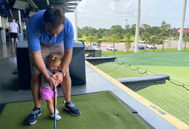 Dr. Kevin Cronin playing golf with 2 year old daughter