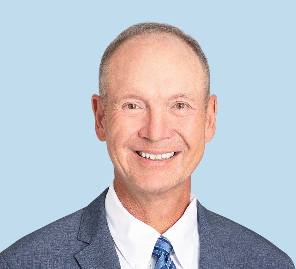 Dr. Mighell professional headshot wearing grey suit and blue striped tie