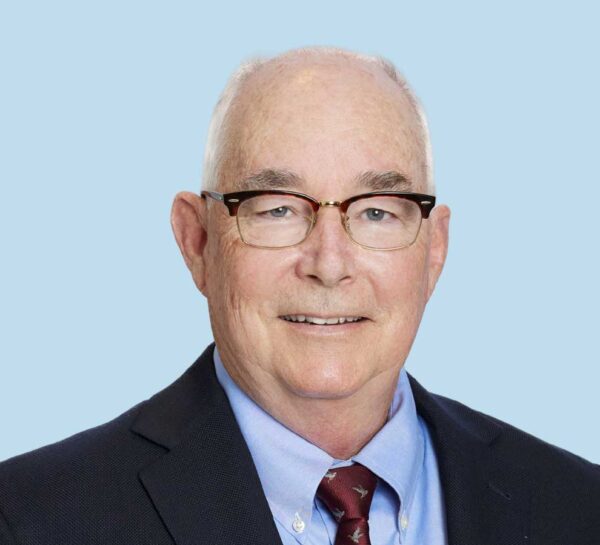 Mark Torke, MD professional headshot wearing black suit and red tie with bird silhouettes