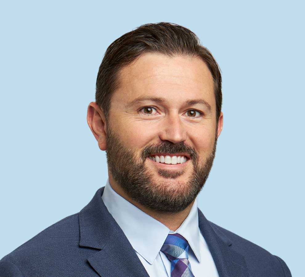 Michael C. Doarn, DC professional headshot wearing dark blue suit with bright blue tie