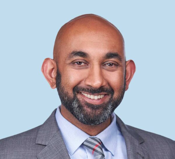 Neil S. Kumar, MD, MBA professional headshot wearing gray textured suit with striped tie