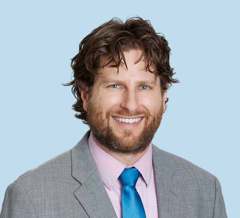 Peter Howard, MD professional headshot wearing gray suit and bright blue tie