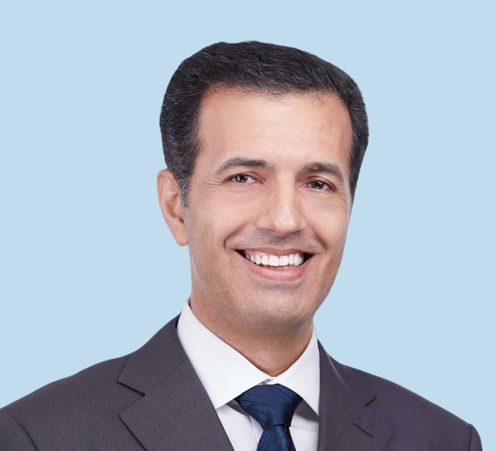 Reza Alavi, MD professional headshot wearing dark gray suit and navy blue tie