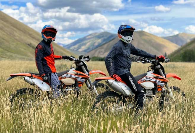 Dr. Seth Gasser riding dirt bikes in a field with mountains in the distance