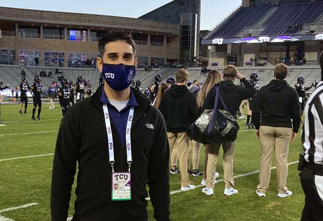 Dr. Shaan Mehta standing on TCU football field with collage students