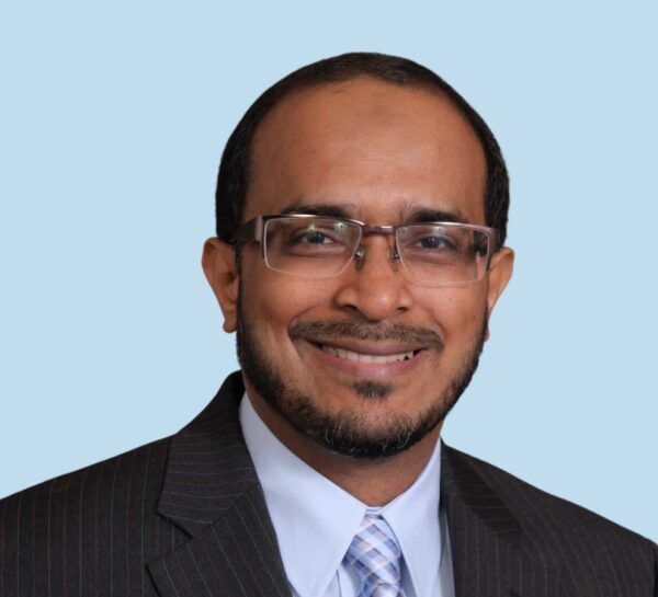 Syed M. Zaffer, MD professional headshot wearing black pinstripe suit and plaid tie