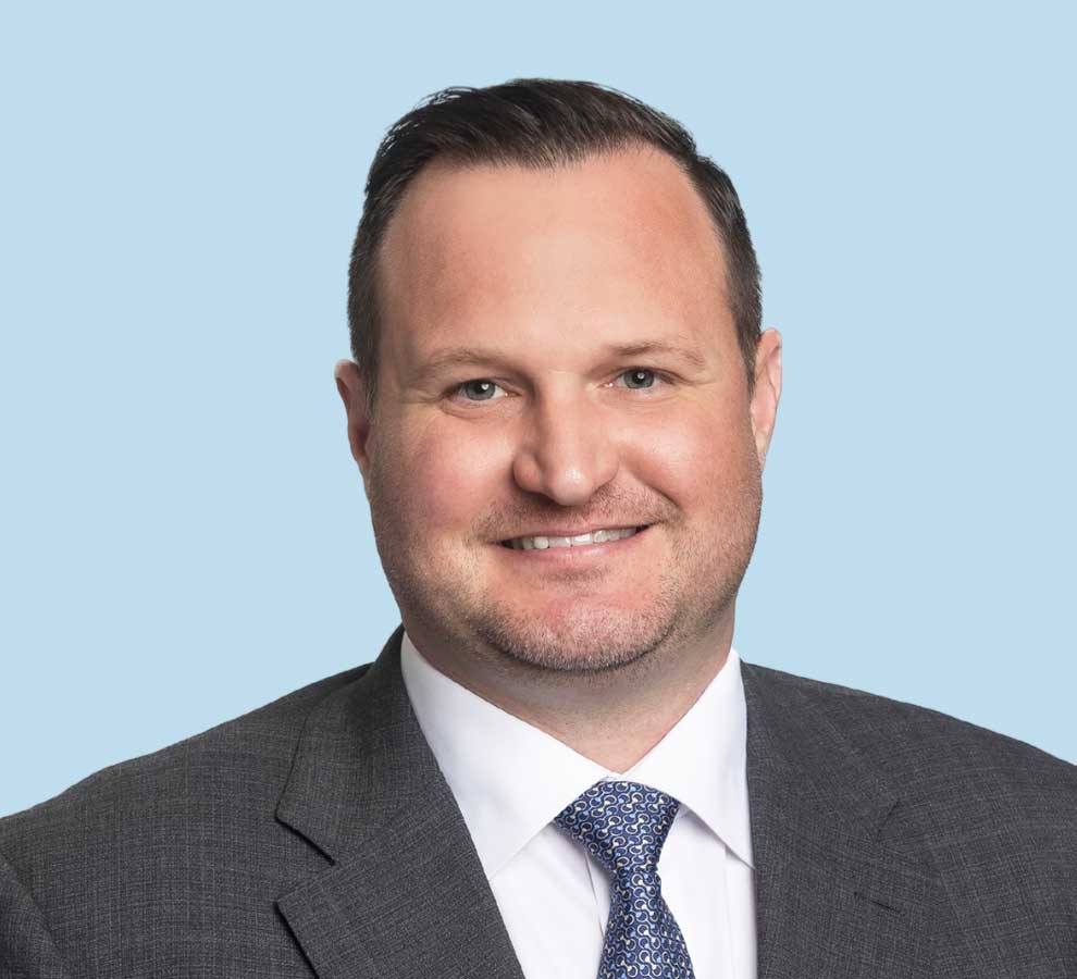 Thomas Auld, MD professional headshot wearing charcoal suit with blue patterned tie