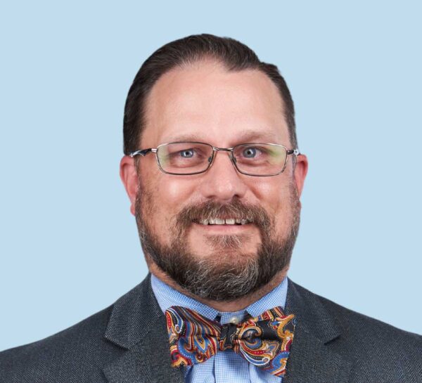 Trey Remaley, DO professional headshot wearing dark gray suit with patterned bowtie