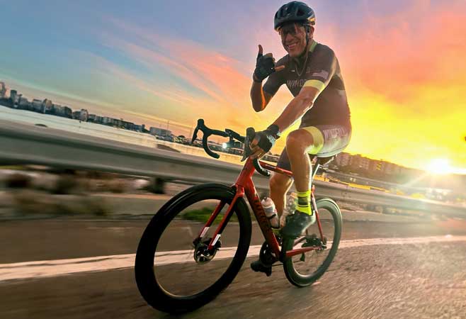 Dr. William Cottrell bicycling against a vivid sunset