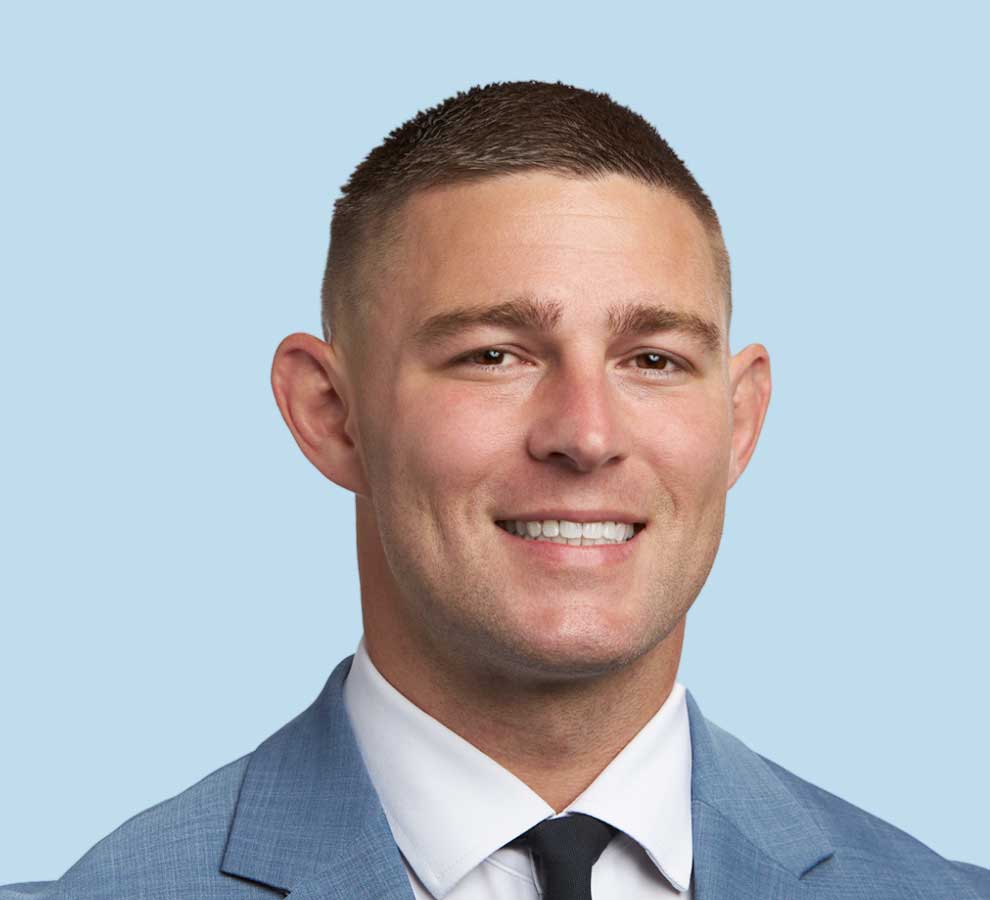 Zachary Wells, DO professional headshot wearing slate blue suit and black tie