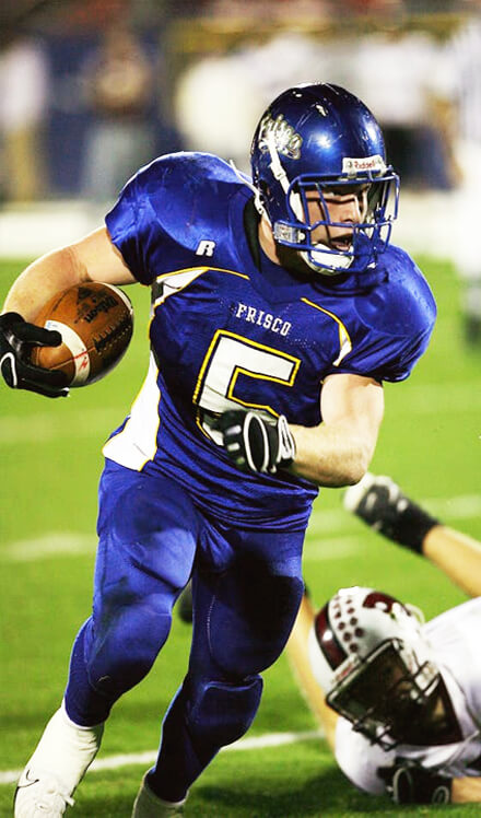 football player holding football while running on field