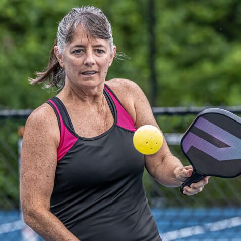 senior active woman playing pickleball