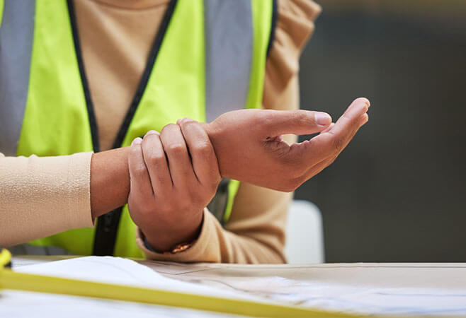 Female construction worker with sprained wrist symptoms in her office.