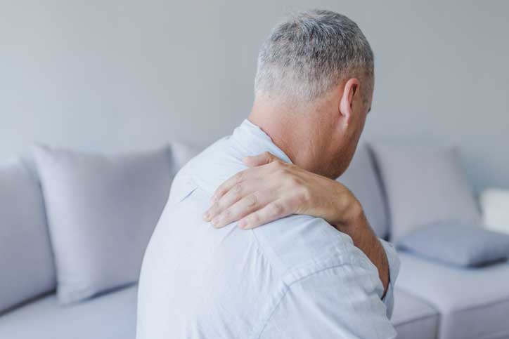 Man suffering from neck or shoulder pain at home