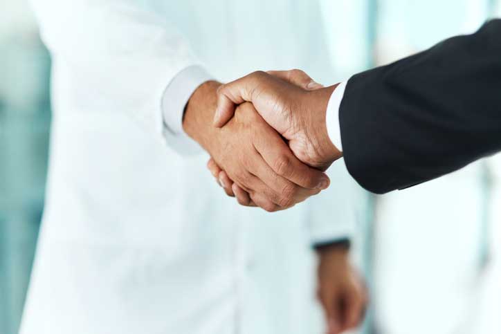 Cropped shot of a doctor shaking hands with a businessman in a hospital