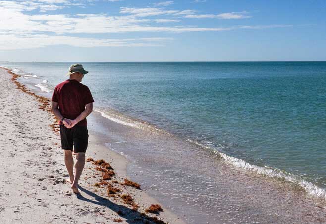 Man walks along Gasparilla beach after recovering from total ankle replacement surgery